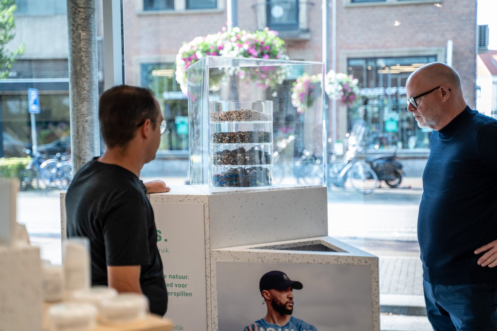 Two customers in conversation beside an in-store product collection display at a Dutch retail store